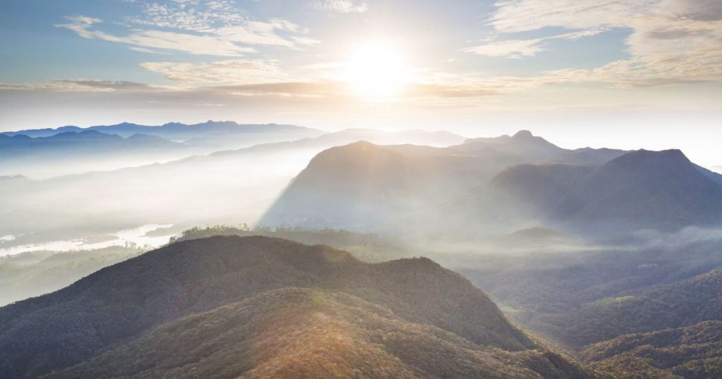 這張圖片展示了斯里蘭卡著名的亞當峰日出，山巒疊嶂，晨光照耀，霧氣繚繞，呈現出一幅壯麗的自然景觀。