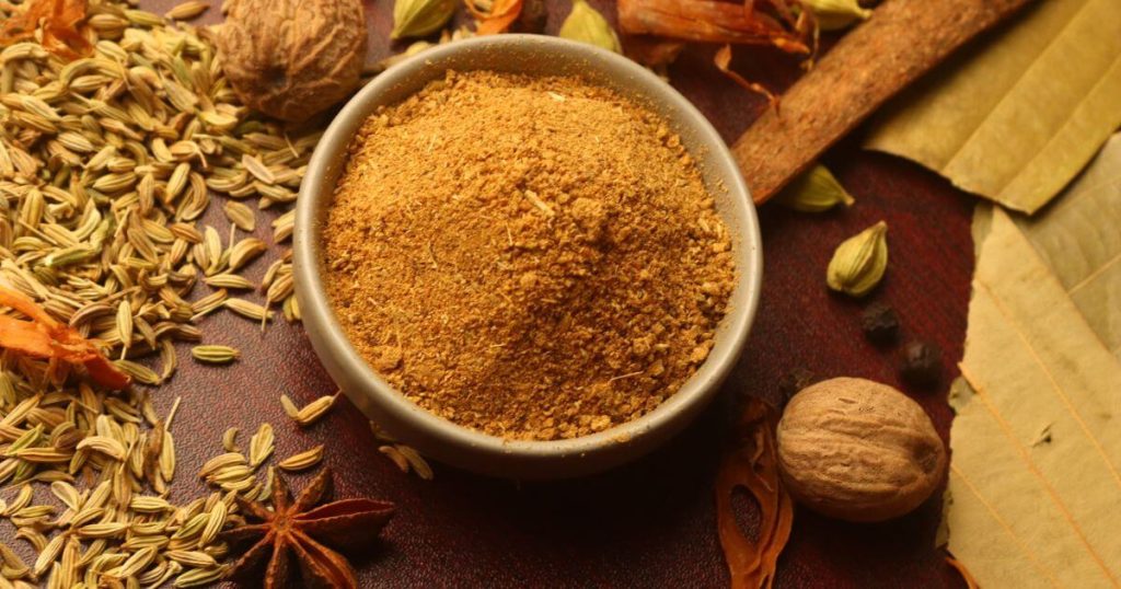 圖片展示了一碗咖哩粉，四周圍繞著茴香、豆蔻和肉豆蔻等香料，象徵著咖哩粉的多層次風味。