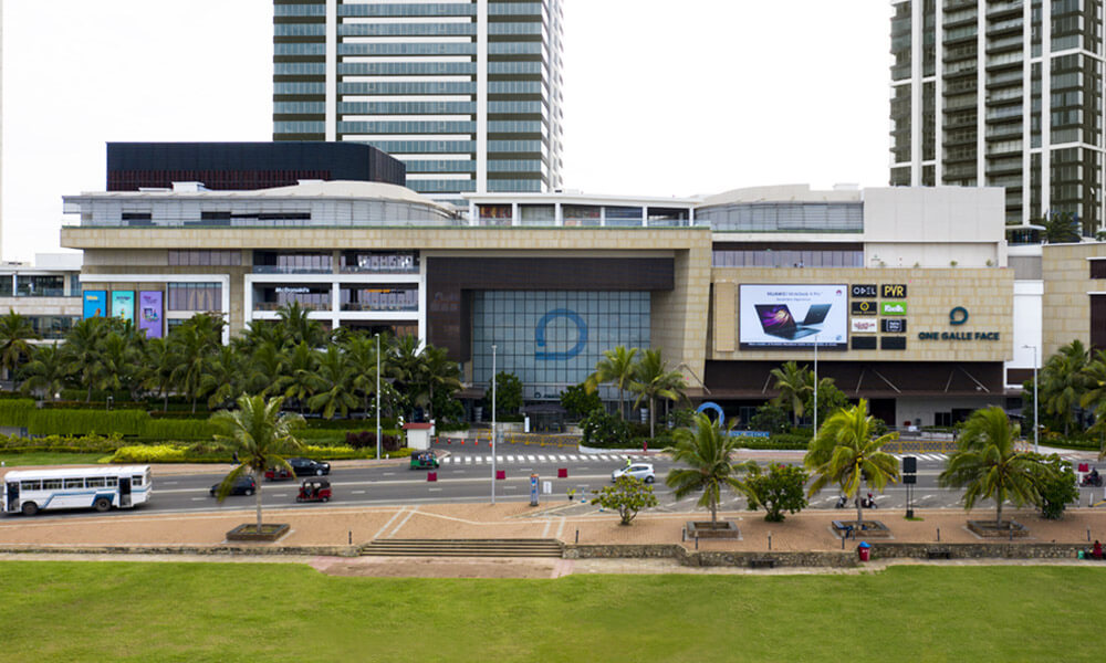 該圖片展示了斯里蘭卡科倫坡著名的One Galle Face購物中心建築外觀，周圍棕櫚樹環繞，呈現高檔購物和娛樂設施的氛圍。此購物中心是斯里蘭卡旅遊和購物的重要地標之一。