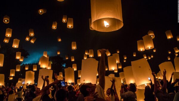 圖片中滿天的天燈緩緩升起,照亮夜空,數百名參與者仰望天燈,雙手高舉釋放,氣氛熱烈且莊嚴。現場燈光柔和溫暖,象徵祈福、願望和團聚,常見於亞洲佛教節慶,如泰國水燈節或元宵節。這張照片完美捕捉集體祈福與節慶的感動時刻,適合用於介紹宗教慶典或旅遊活動。