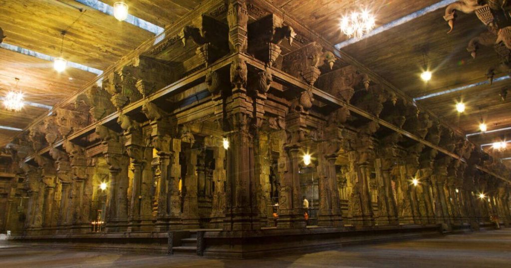 圖片展示了Sri Ponnambala Vaneswarar古廟的內部，古老的石柱和精緻的雕刻藝術充滿了歷史與宗教氛圍，燈光映照下顯得莊嚴神聖。