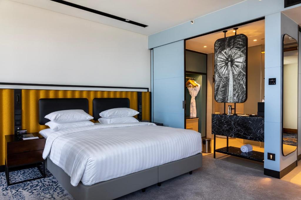 圖片中展示了Courtyard by Marriott Colombo一間精心設計的豪華飯店客房，柔軟的雙人床鋪配有白色床單，牆面以金色和灰色相間的設計為主，房內設有現代化的浴室，整體設計展現出簡約與奢華的融合。