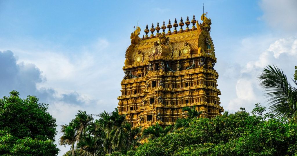 此圖片展示了位於斯里蘭卡賈夫納的壯麗金色寺廟,寺廟建築精緻且富麗堂皇,頂部裝飾有精美的雕刻和宗教符號,周圍環繞著茂密的椰子樹和綠植,背景是一片晴朗的藍天。此圖片強調了寺廟的輝煌與其在賈夫納地區的重要宗教地位。