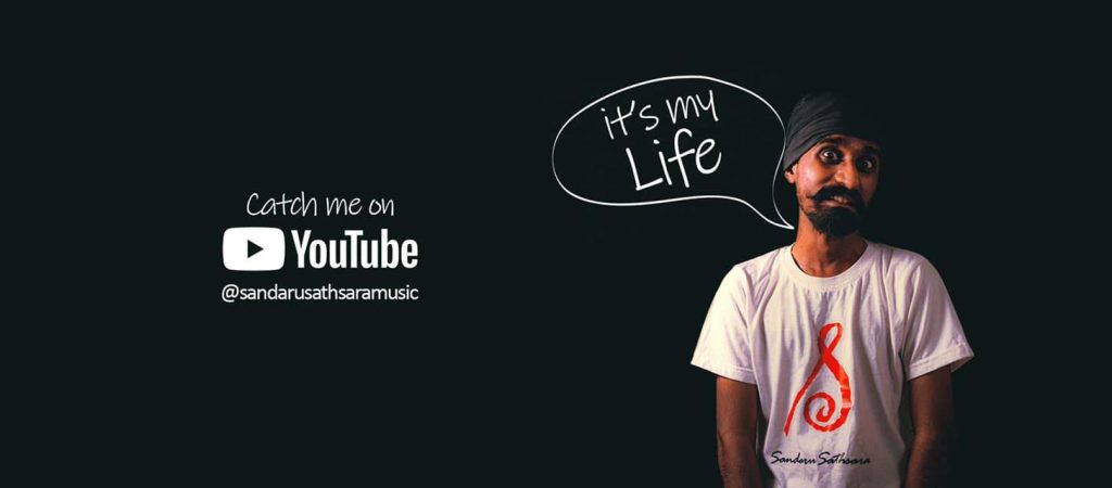 圖片展示一位戴頭巾的男子,穿著印有「Sandaru Sathsara」標誌的白色T恤,背景為黑色,旁邊有「It's my life」的手繪字樣,以及「Catch me on YouTube @sandarusathsaramusic」的宣傳語,整體設計簡潔而有個性,吸引觀眾點擊觀看其頻道內容。